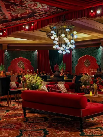 Another perspective of the lounge area, showing the arrangement of red velvet sofas and the custom-printed ceiling. The design creates a cohesive and deeply immersive guest experience.