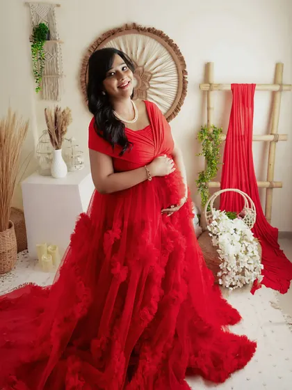A happy and bright portrait in a red ruffled gown. The boho setup with white flowers provides a beautiful contrast.