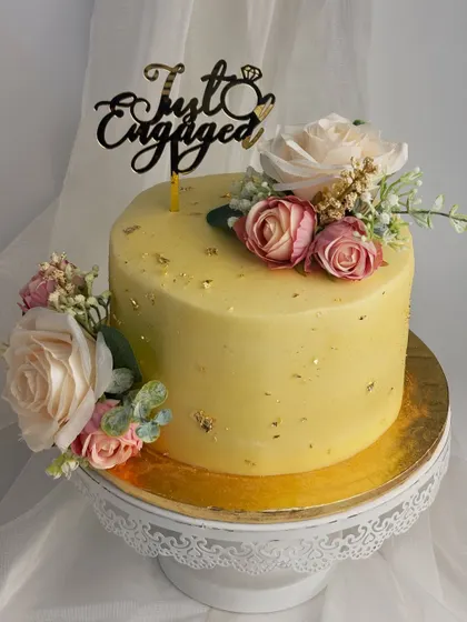 An elegant engagement cake with a simple yellow buttercream finish, accented with gold leaf and beautiful artificial flowers. Sometimes, simplicity is the ultimate sophistication.