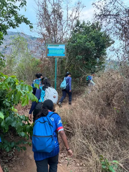 A group of trekkers with backpacks walking past a trail marker. We handle all the planning for your custom group trek so you can focus on the experience.