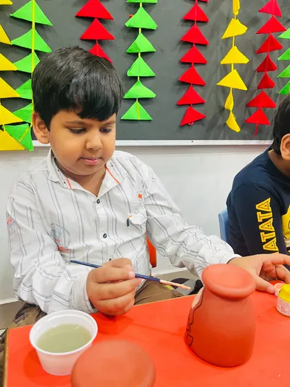 A student carefully painting his terracotta diya holder during our Diwali workshop.