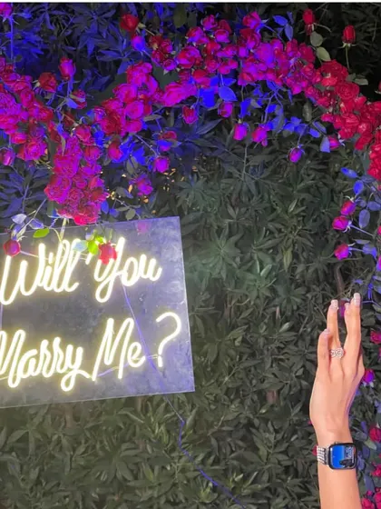It's all in the details. A close-up of the "Will you Marry Me?" neon sign nestled among a beautiful flower wall, with the engagement ring making its debut.