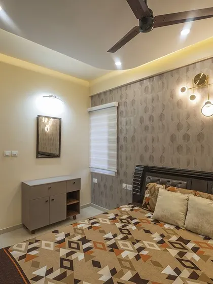 A full view of the guest bedroom, showing the bed, side table, and dresser, all unified by a warm, earthy color scheme.