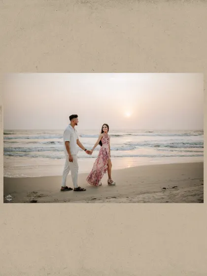 A wide shot of a couple taking a romantic walk along the shoreline at sunset. This photo emphasizes the beautiful scenery of a destination beach photoshoot.