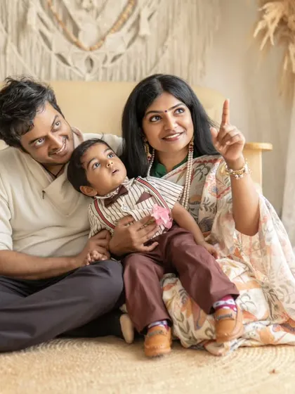 A lovely family portrait including the parents and grandparents. The mother points to something off-camera, creating a natural and engaging scene for everyone.