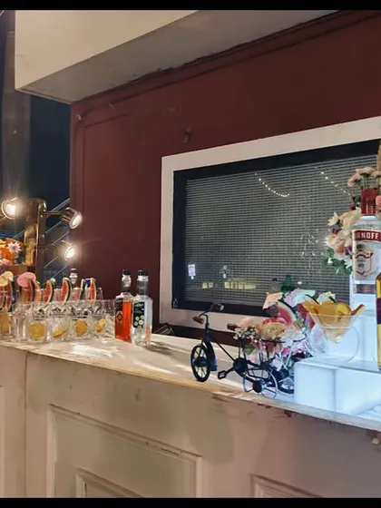 A beautiful house party bar setup on a white console. The illuminated risers, floral arrangements, and decorative tricycle add a whimsical and elegant touch.