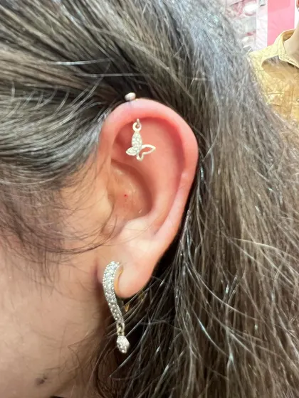 A delicate butterfly hanging from the helix, paired with a sparkling drop earring on the lobe for a light and airy look.