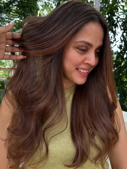 A happy client showing off her vacay-ready hair. The color is fresh, and the style is effortless.