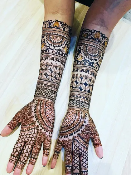 A beautiful example of a full coverage bridal mehendi. The design uses bands of geometric and floral patterns to create a rich, textured look that extends to the elbows.