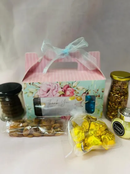 This image shows the contents of one of the baby shower return gift boxes. I included a scented candle, a jar of cookies, almonds, chocolates, and a jar of trail mix.
