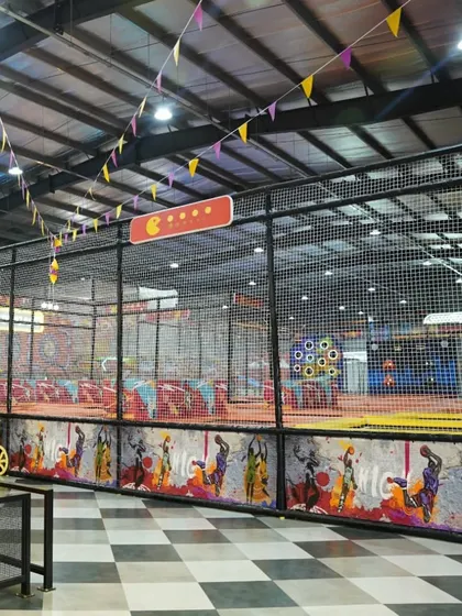 A wide shot showing the scale of our facility, with the checkered floors, cafe seating, and the expansive, netted play area.