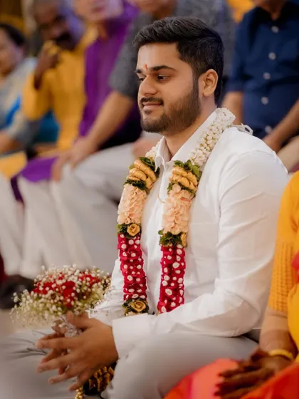 A portrait of the groom, seated and waiting with a bouquet, looking calm and happy during the engagement ceremony.