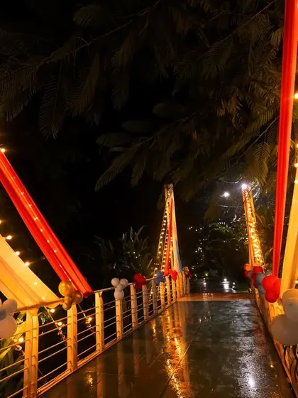 A beautifully decorated bridge at a carnival-themed event. The bridge is draped with colorful fabrics and lit with string lights, creating a magical pathway for guests.