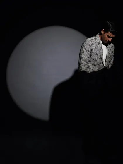Using dramatic lighting, this shot puts the focus squarely on the patterned suit jacket, creating a sense of mystery and high fashion intrigue.