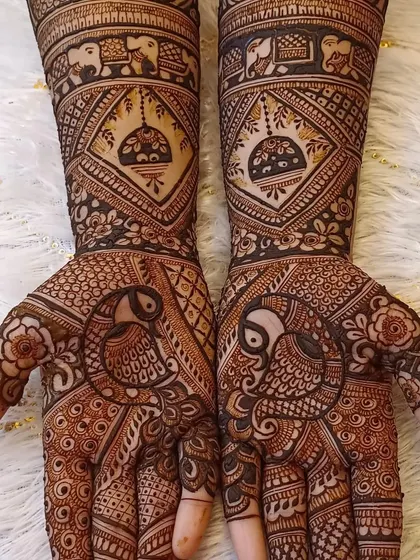 A very symmetrical and clean bridal design with bold peacocks on the palms and jhumki motifs on the arms.