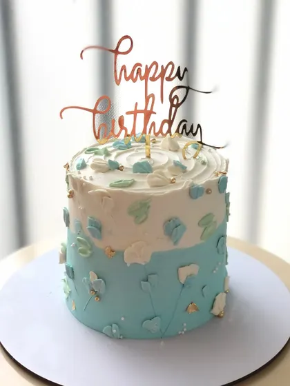 A minimalist cake with an abstract blue and white design and touches of gold leaf.