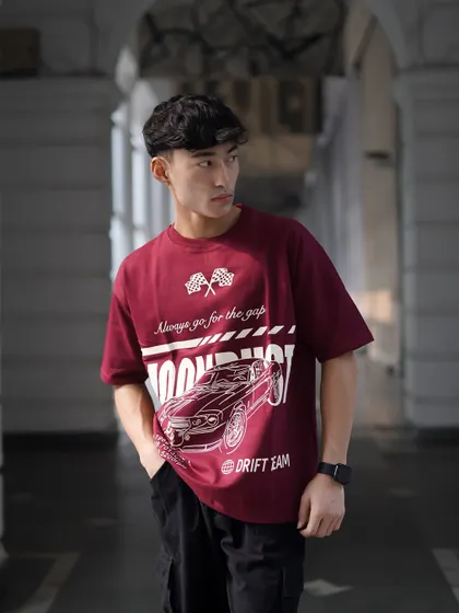 A three-quarter shot of the male model, showing how the oversized tee fits. The natural light from the side defines his features and the texture of the shirt.