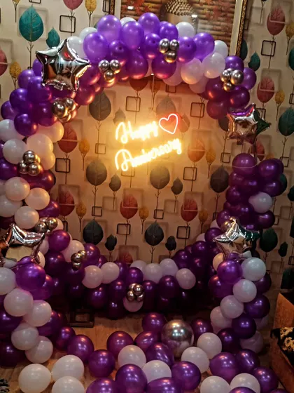 We created this vibrant anniversary backdrop using purple and white balloons, accented with silver star-shaped foils. The "Happy Anniversary" neon sign adds a romantic touch to the celebration.