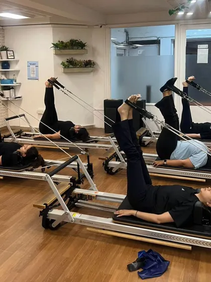 Our small group reformer classes allow for personalized attention, as seen here with members working on leg circles with straps.
