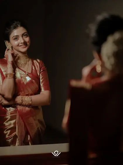 A bride smiles at her reflection in the mirror, a happy moment during her getting-ready process.