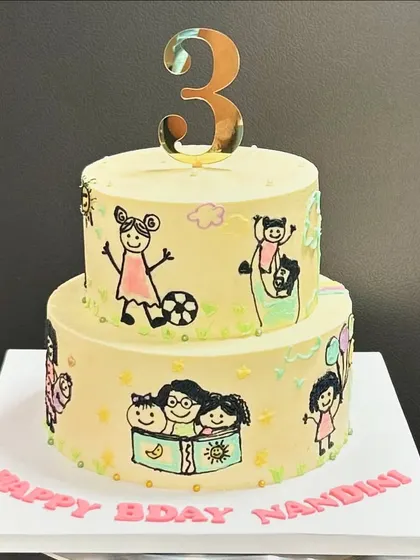 The full view of the two-tier doodle cake for Nandini's 3rd birthday. Each little drawing represents a special memory or hobby, creating a cake that's as meaningful as it is delicious.