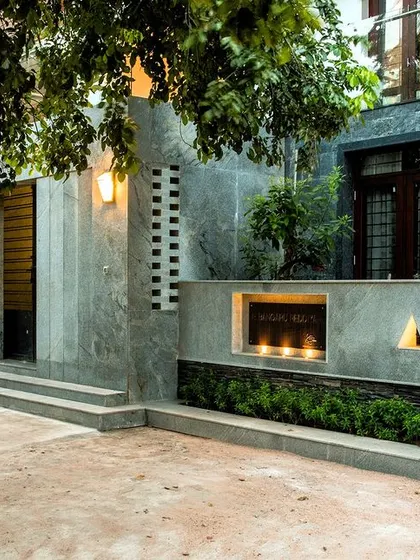 The boundary wall and entrance area feature a mix of materials and integrated lighting, creating an inviting and modern street presence for the renovated home.