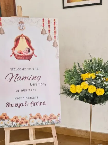 We love creating elegant welcome signs for naming ceremonies. This design for Shreya and Arvind's baby features traditional motifs like temple bells and a baby in a thottil (cradle), setting a warm and inviting tone for guests.