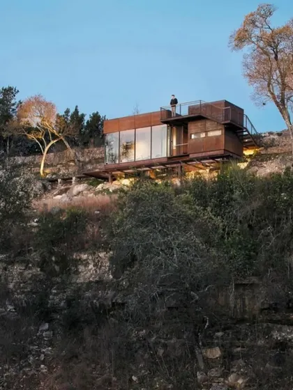 This is our vision for hillside living. A modular home built with a rustic, weathered steel exterior that blends into the rocky terrain, featuring a rooftop deck to take in the stunning views.