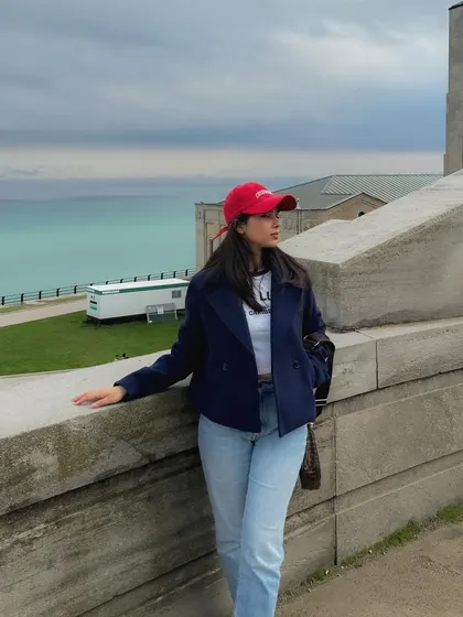 A fun weekend outfit with a red cap, navy jacket, and jeans, perfect for a cool day.