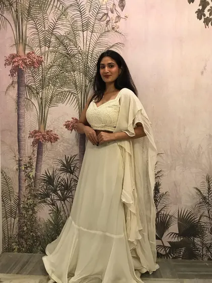 A full-length view of the off-white fusion set against a botanical backdrop, highlighting its graceful flow.