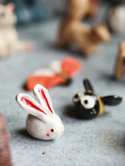 A tiny white rabbit with pink ears and a buzzing bee, showcasing the playful and imaginative possibilities of clay.