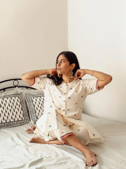 A candid lifestyle image on a bed, capturing a natural moment of the model adjusting her earrings. These shots are effective for social media content as they feel authentic and unposed.