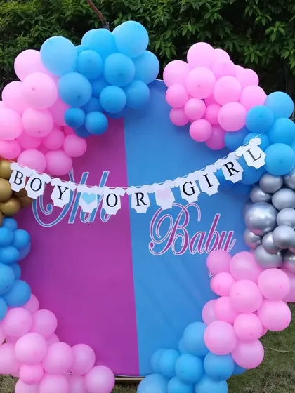 A "Boy or Girl" themed baby shower decoration. The backdrop is split between pink and blue, surrounded by a matching balloon arch, building anticipation for the big reveal.