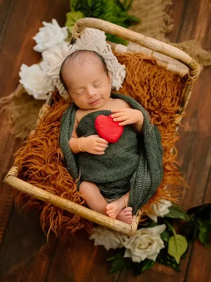 Holding a heart full of love. This sleeping newborn, wrapped in a deep green swaddle, represents the precious gift of new life.