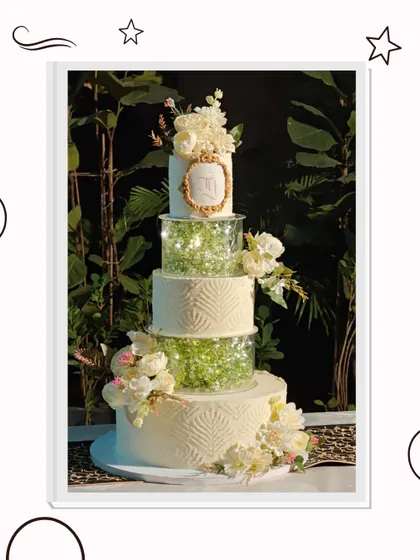 This multi-tiered wedding cake is a true showstopper, designed to be the centerpiece of a grand celebration. It features elegant textures, separator tiers filled with delicate baby's breath, and is adorned with handcrafted sugar flowers and a custom monogram.