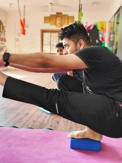A student uses a block to improve balance and stability in this one-legged squat, building strength in the standing leg.