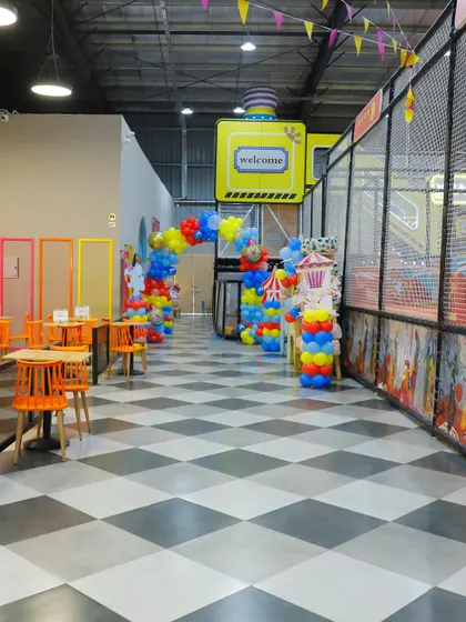A circus or carnival-themed birthday party setup, with bright primary colors and fun balloon columns.