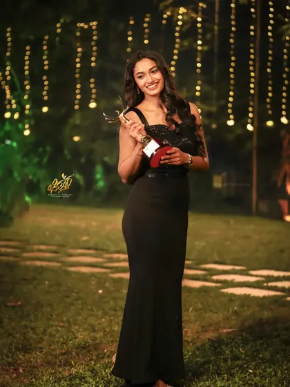 A full-length shot of actress Reeshma Nanaiah holding her award. This portrait combines the celebratory moment with an elegant pose, ideal for event coverage.
