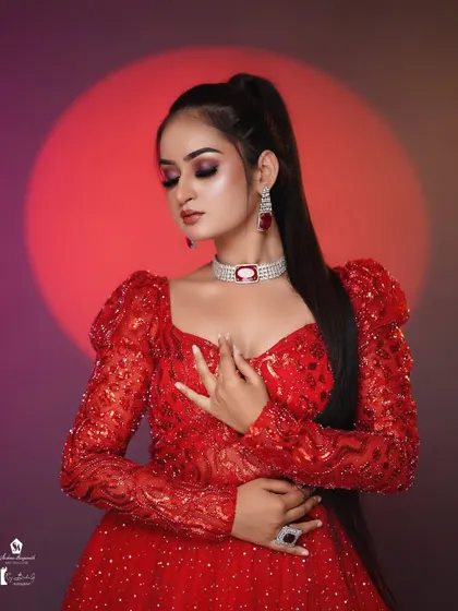 A bold and beautiful look in a sparkling red gown. The dramatic red eyeshadow and sleek ponytail create a high-fashion statement.