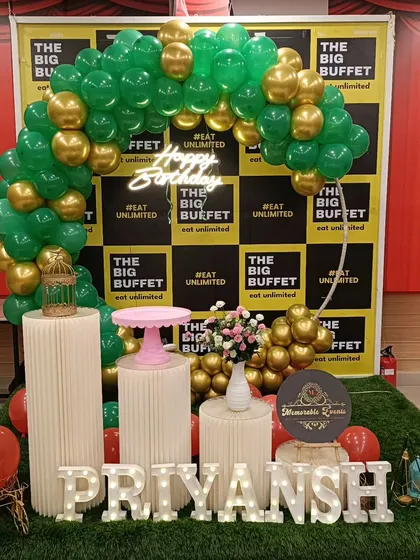 A birthday setup for a client named Priyansh at The Big Buffet. This decor includes a circular balloon arch, themed pedestals, and large marquee letters spelling out the name on a turf mat.