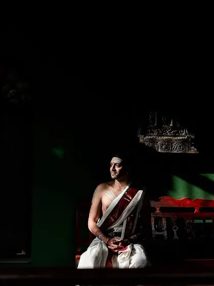 A groom sits in a quiet, contemplative moment, with dramatic lighting casting shadows across the room. A powerful and artistic portrait.