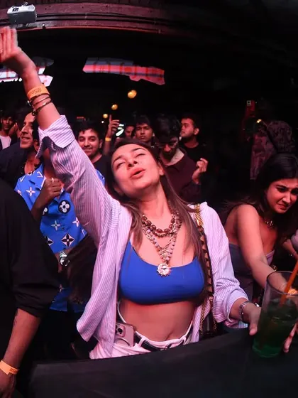 A partygoer with her hand in the air, completely lost in the music.