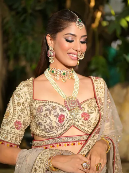 A gentle, smiling portrait. The soft pink tones in the makeup complement the floral embroidery on her lehenga, creating a harmonious and beautiful look.