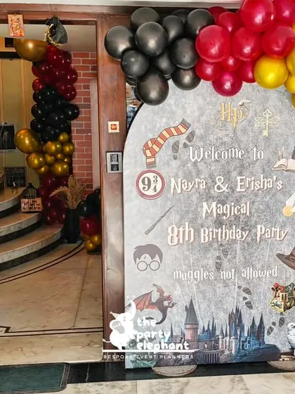 The entrance to the Harry Potter party featured a custom welcome sign and a balloon arch in Gryffindor colors of scarlet and gold, complete with a Nimbus 2000 broomstick prop.