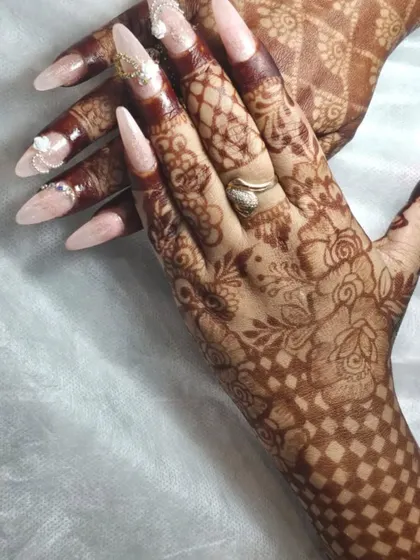 A full view of how custom nails complete the bridal look. The long, almond-shaped nails with subtle 3D art and glitter perfectly extend the beauty of the intricate henna design.