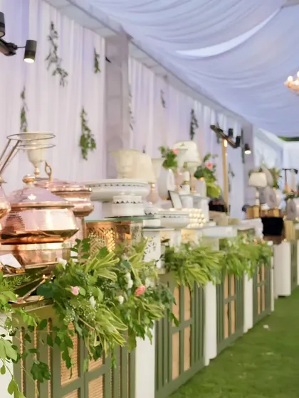 An expansive view of an elegant buffet setup for an outdoor corporate luncheon. Our signature hammered copper serveware and fresh floral arrangements create a visually stunning centerpiece for any gathering.