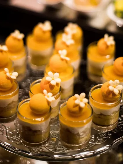 A tray of beautiful mango mousse desserts. The vibrant colour and delicate floral garnish make this a refreshing and elegant end to any meal.
