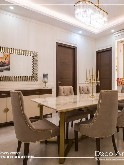 An elegant fusion of modern minimalism and classic detailing. This dining space features a sleek marble-top table, neutral-toned upholstery, and a statement chandelier to complete a look of sophisticated dining.