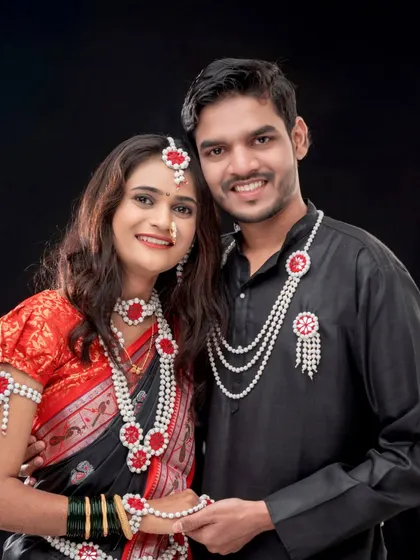 A lovely couple portrait from a Makarsankranti themed session. They are posed closely together, showcasing their matching black outfits and traditional *halwyache dagine*.