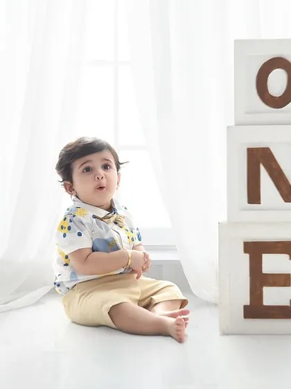 Another angle from a classic first birthday shoot. The focus is entirely on the baby's curious expression as he sits beside the "ONE" blocks.